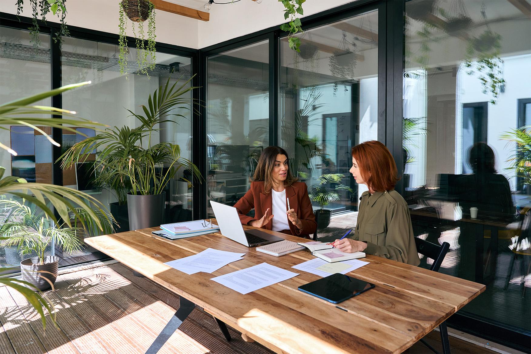 Twee professionals overleggen Twee professionals overleggen aan een tafel in een moderne kantooromgeving